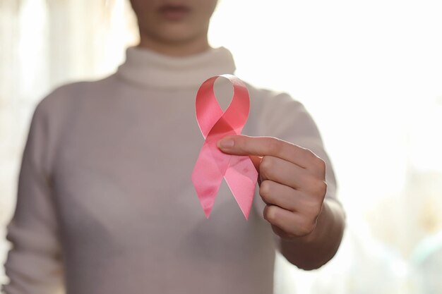 Het rode lint van het meisje. Het meisje houdt een rood lint vast. Gezondheidsconcept rood lint. Borstkanker.