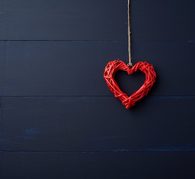 Het rode rieten decoratieve hart hangen op bruine kabel