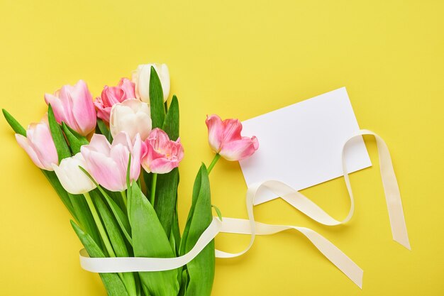 Het roze boeket van tulpenbloemen op voorzijde van gele achtergrond.