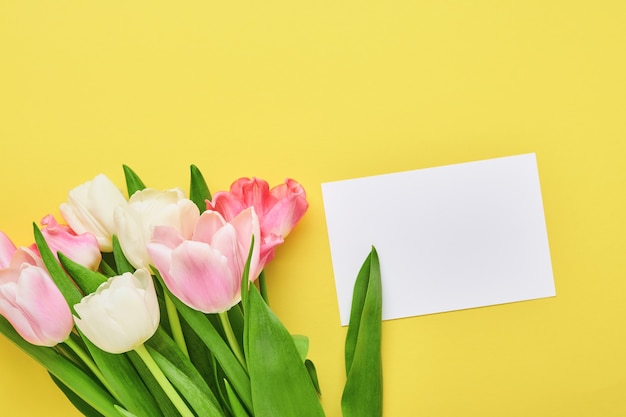 Het roze boeket van tulpenbloemen op voorzijde van gele achtergrond.