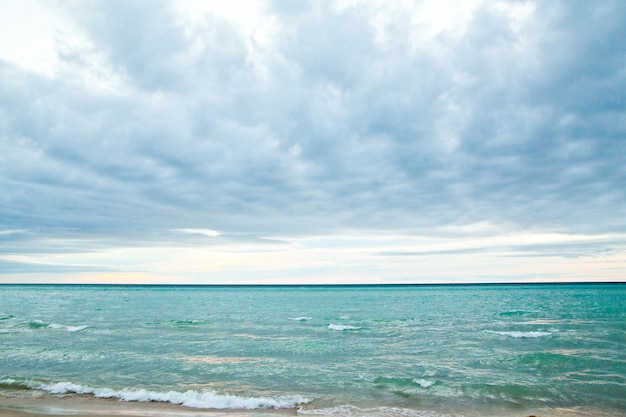 Het rustige strand van het meer van Michigan met zachte golven en bewolkte lucht