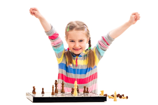 Het schattige meisje van de leerplichtige leeftijd voelt zich buitengewoon gelukkig over het winnen van schaken geïsoleerd op een witte achtergrond