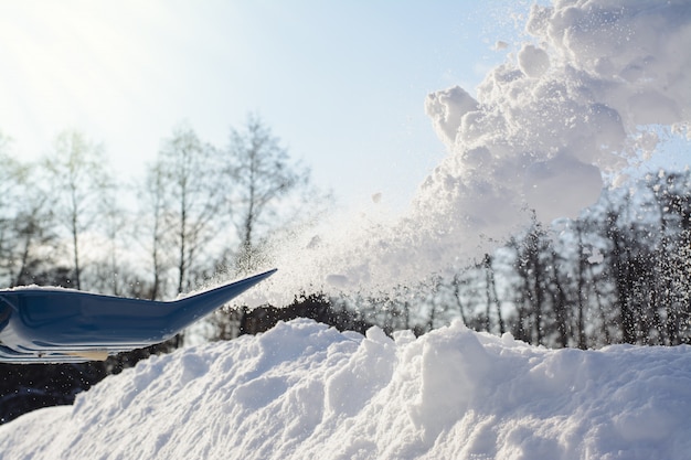 Het scheppen van sneeuw in zonnige de winterdag. Sneeuw verwijderen van de oprit