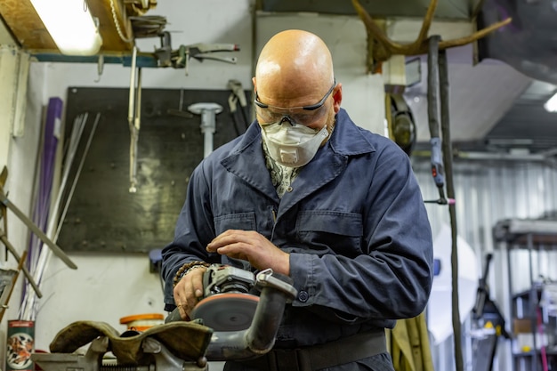 Het scherpe staal van de zware industriearbeider met hoekmolen bij de autodienst