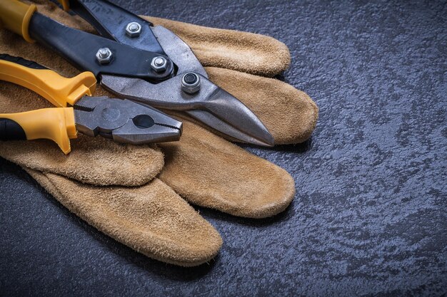 Het scherpe tin knipt de veiligheidshandschoen van het tangleer op zwarte achtergrond