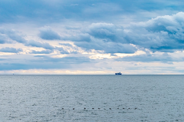 Het schip vaart op zee tegen de achtergrond van een prachtige bewolkte hemel.