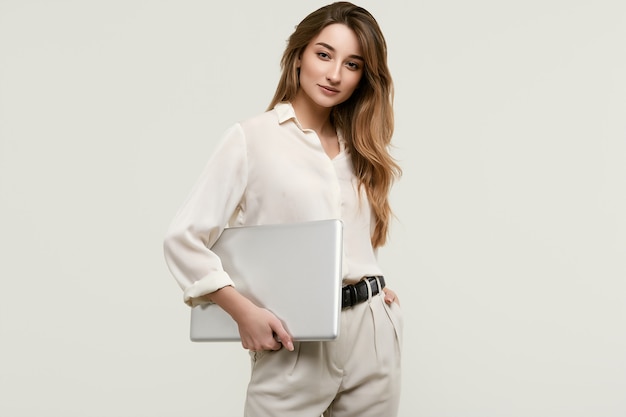 Het schitterende donkerbruine model stellen in witte kleren met laptop