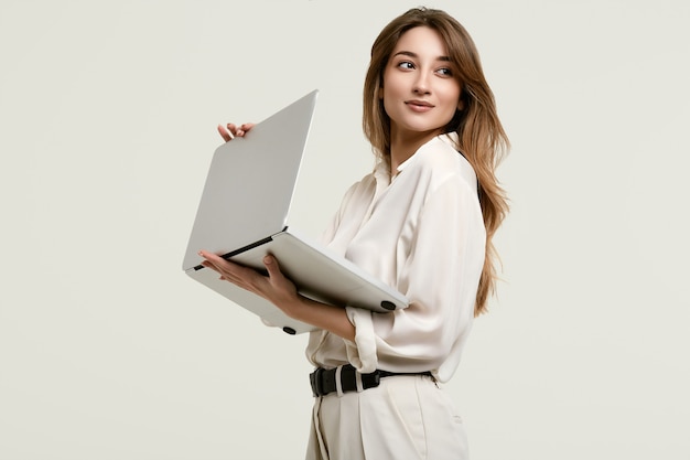 Het schitterende donkerbruine model stellen in witte kleren met laptop