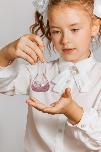 Het schoolmeisje mengt de vloeistof in de kolf voert een chemische analyse uit Scheikunde bestuderen