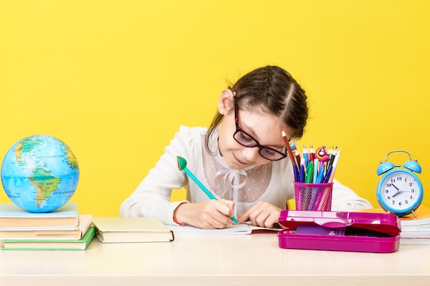 Het schoolmeisje zit aan het bureau en denkt na over de beslissing van de taak