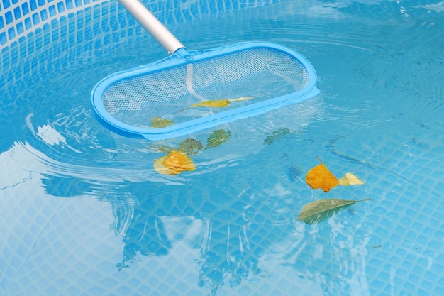 Foto het schoonmaken van een zwembad met een mesh skimmer het lange net reinigt gekleurde bladeren van het wateroppervlak