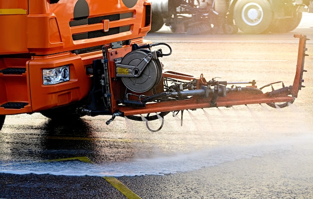 Het schoonmaken van veegmachines wast de stadsasfaltweg met waternevel in de vroege ochtend