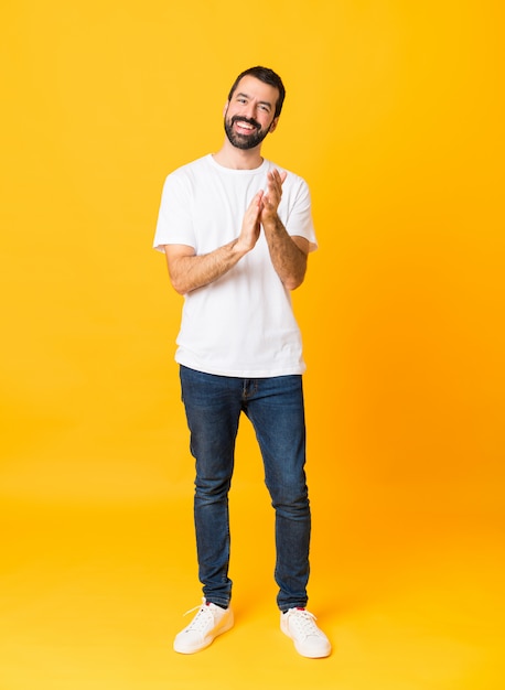 Het schot van gemiddelde lengte van de mens met baard over geïsoleerd geel het toejuichen na presentatie in een conferentie