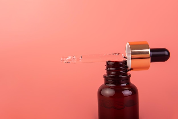 Het serum met vitamines Transparante etherische olie druppelt van pipet in een bruine glazen fles