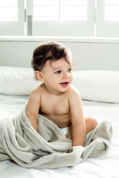 Het shirtless babyjongen spelen met handdoek op bed