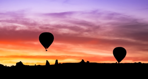 Het silhouet van de hete luchtballon in bergen bij zonsopgang