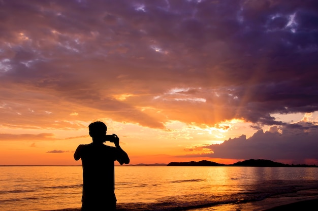 Het silhouet van de mens houdt herinneringen met cameratelefoon in zijn hand