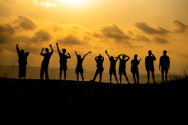 Het silhouet van een groep mensen viert succes op de heuveltop.