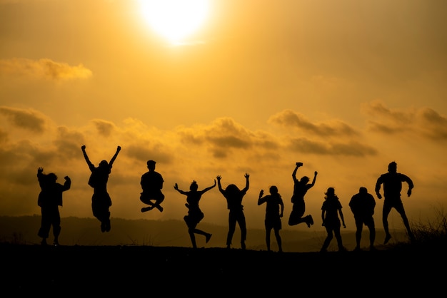 Het silhouet van een groep mensen viert succes op de heuveltop.