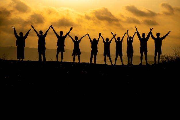 Het silhouet van een groep mensen viert succes op de heuveltop.