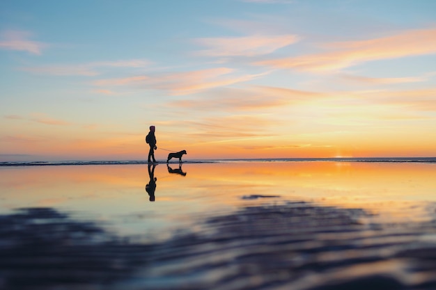 Het silhouet van een man tegen de achtergrond van een zonsondergang op een meer of zee een vrouw of een
