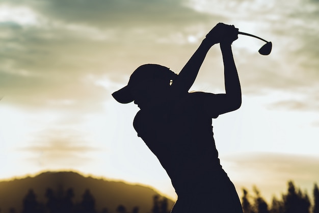 Het silhouet van jonge vrouwelijke golfspeler raakte vegen en houdt golfcursus golfschommeling doen, oefent zij uit voor ontspannen tijd