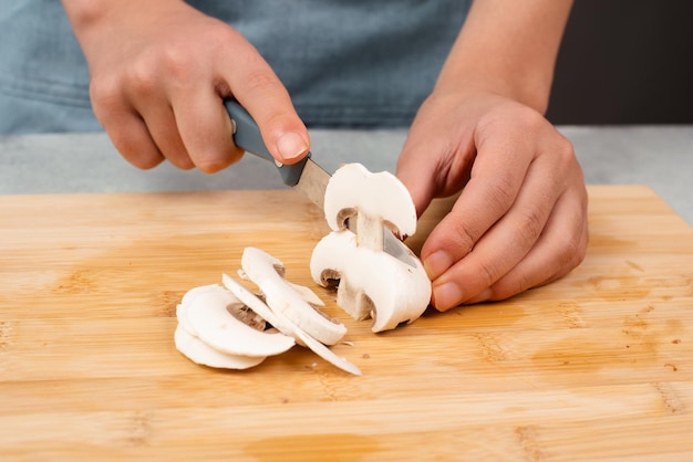 Het snijden van champignonpaddestoelen op een houten plank bereidt een gezonde salade voor met verse groenten