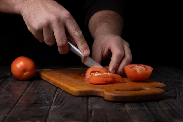 Het snijden van groenten Mannelijke handen snijden van tomaten op een snijplank