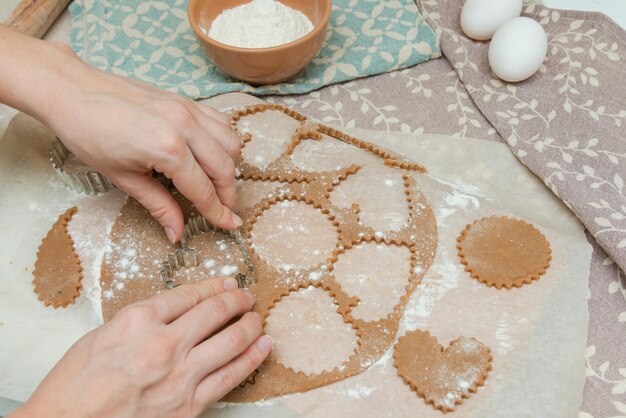 Foto het snijden van koekjes door koekjes snijders vrouw maken met de handen hartvormige koekjes voor valentijnsdag