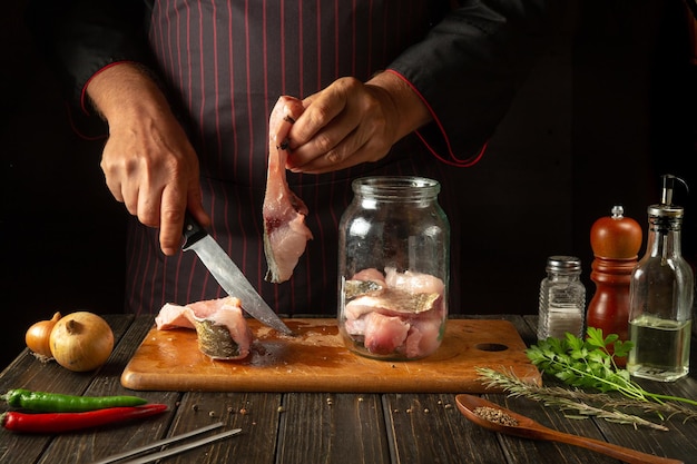 Het snijden van rauwe karpervissen voor het bereiden van haring in een pot of in een blik Het mes in de hand van de kok en steak met vis Het concept van het visdieet