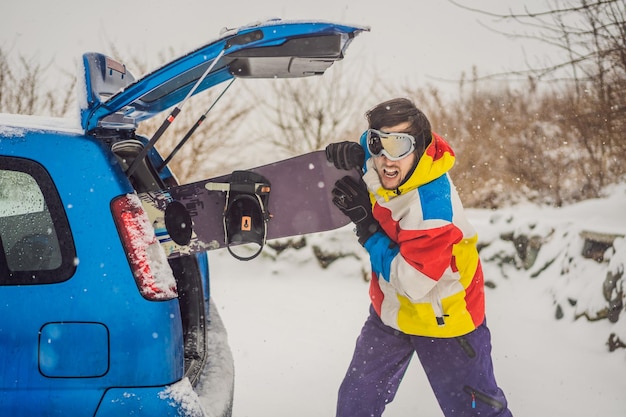 Het snowboard past niet in de auto Een snowboarder probeert een snowboard in een auto te steken Humor leuk