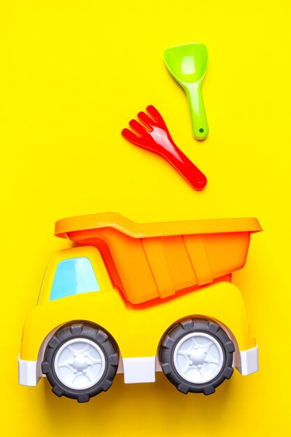 Foto het speelgoed van kleurrijke kinderen - vrachtwagen en schop, lepel op geel