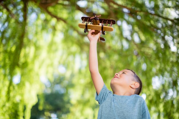 Het spelen van de jongen met een houten stuk speelgoed vliegtuig in park