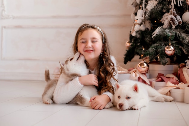 Foto het spelen van het meisje met schor puppy dichtbij kerstboom