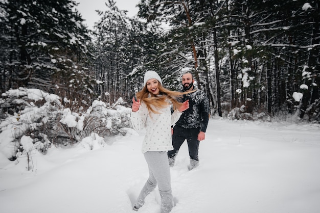 Het spelen van het paar met sneeuw in het bos