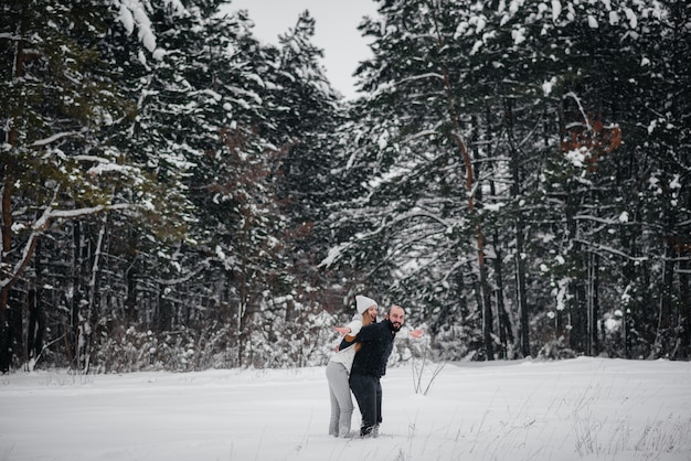 Het spelen van het paar met sneeuw in het bos