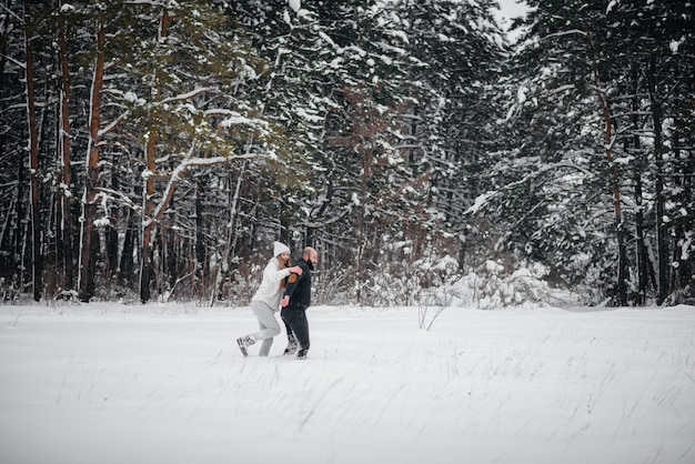 Het spelen van het paar met sneeuw in het bos