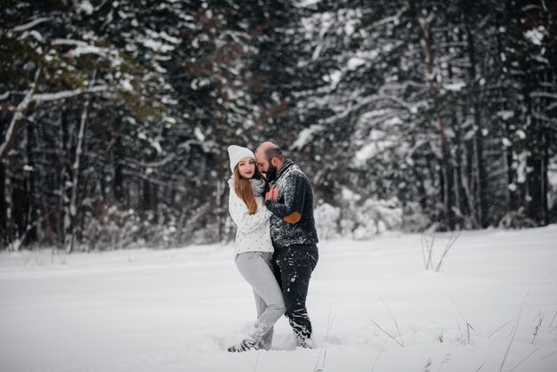 Het spelen van het paar met sneeuw in het bos