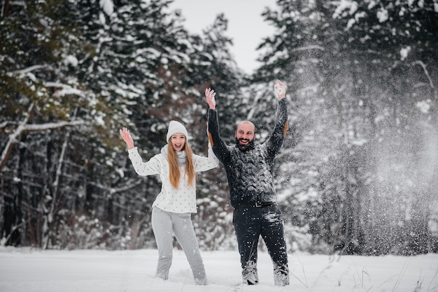 Het spelen van het paar met sneeuw in het bos