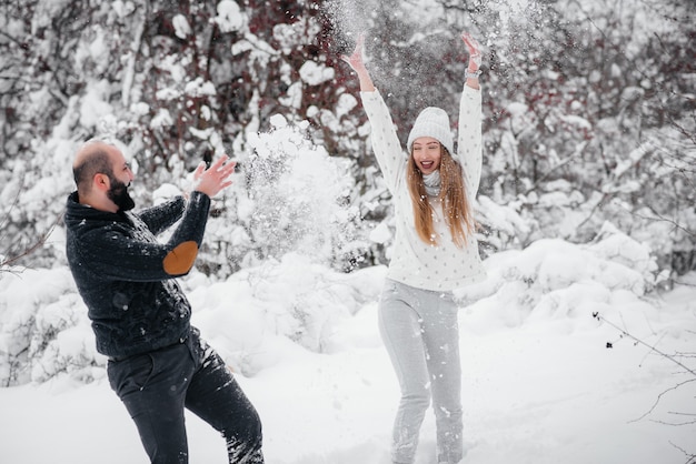 Het spelen van het paar met sneeuw in het bos