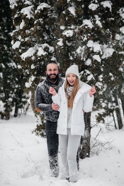 Het spelen van het paar met sneeuw in het bos.