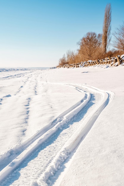 Het spoor van een sneeuwscooter op een bevroren rivier in de sneeuwwinter