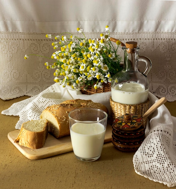 Het stilleven met curatieve madeliefjesmelk en brood op de tafelclose-up