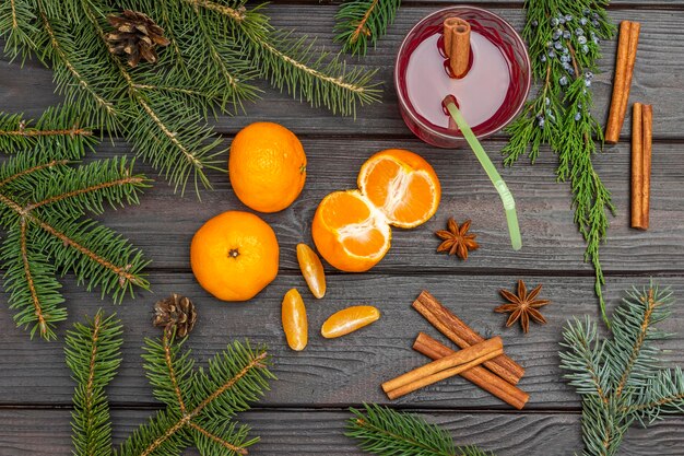Het stilleven van het nieuwe jaar. Glühwein en mandarijnen. Dennentakken en kegels. Kaneelstokjes. Plat leggen. Donkere houten achtergrond.