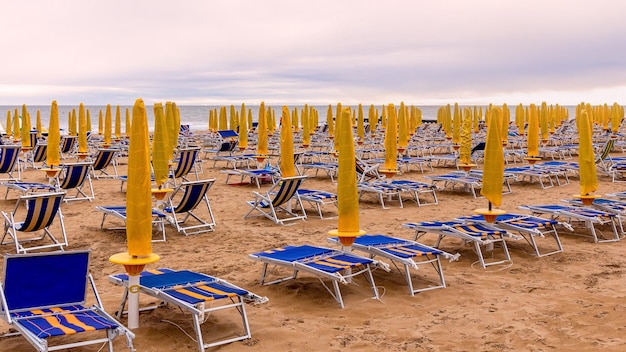 Het strand van Lido di Jesolo. Veel blauwe ligstoelen en gele parasols op het strand.Italië