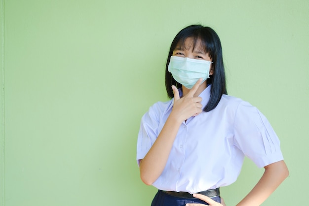 Het studentenmeisje draagt een masker op een groene muur.