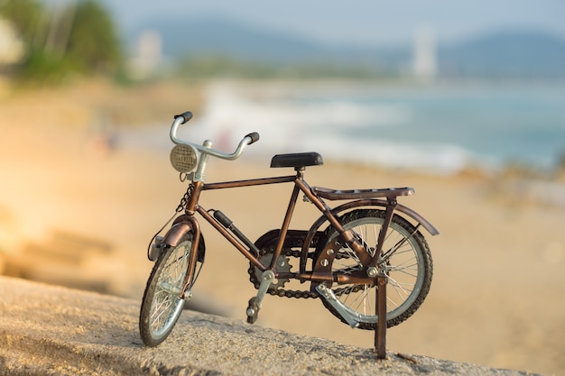 Het stuk speelgoed van het fietstransport op zand overzees strand in de avond zonsonderganghemel