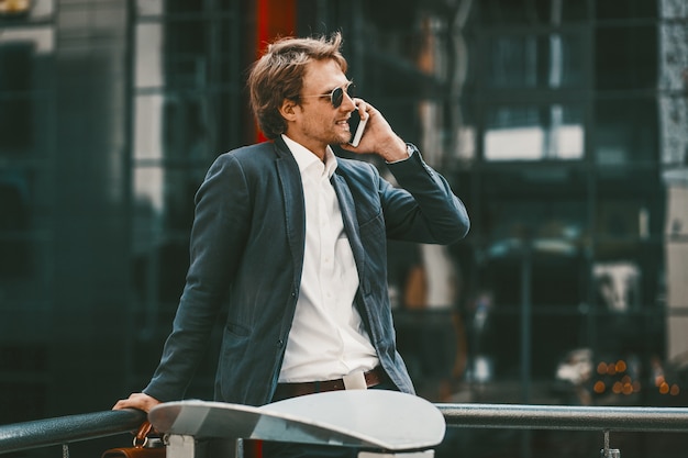 Het succesvolle jonge mens gelukkige glimlachen terwijl het hebben van telefoongesprek