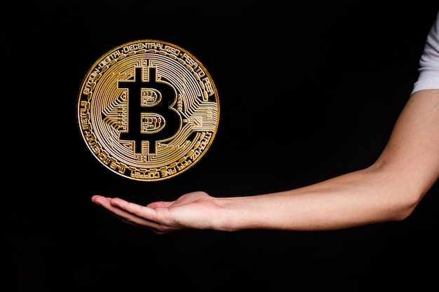 Het symbool van de nieuwe populaire cryptocurrency bitcoin met de afbeelding van handen