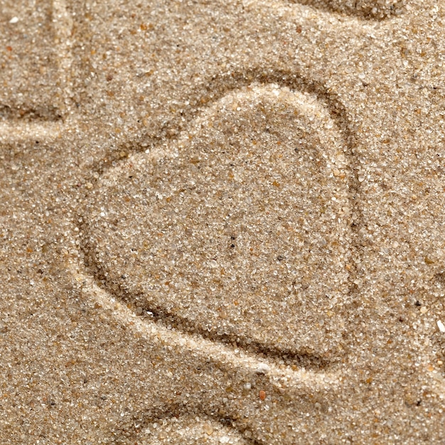 Het symbool van het hart is getekend op schoon zand